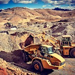 All working together; a CAT front-end loader loads an articulated truck.  The various pieces of equipment work together to excavate & haul ore.  Each executing a vital step towards the mining, crushing, leaching and pouring of gold at the Moss Mine.
